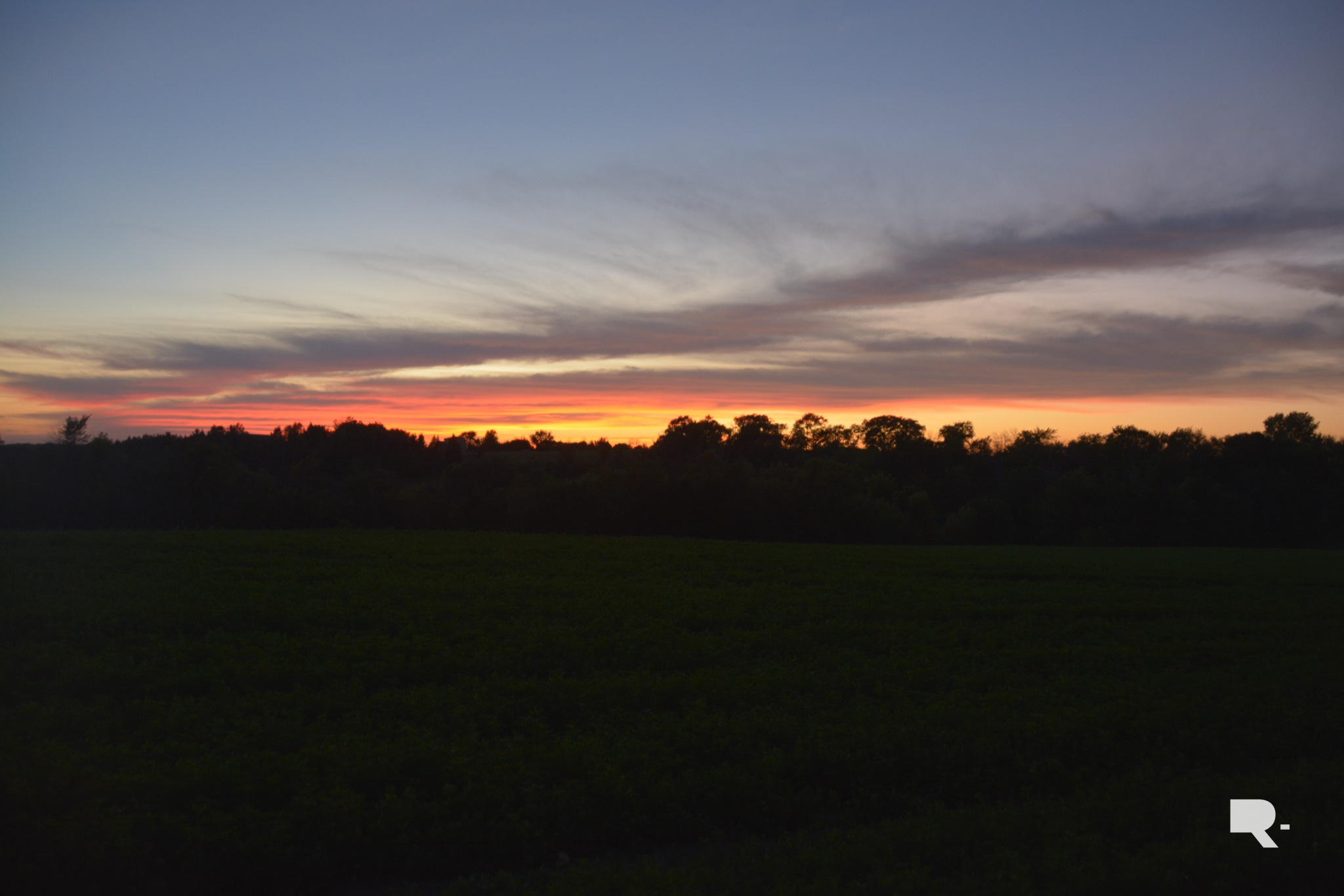 Open field beneath a colorful sunset sky