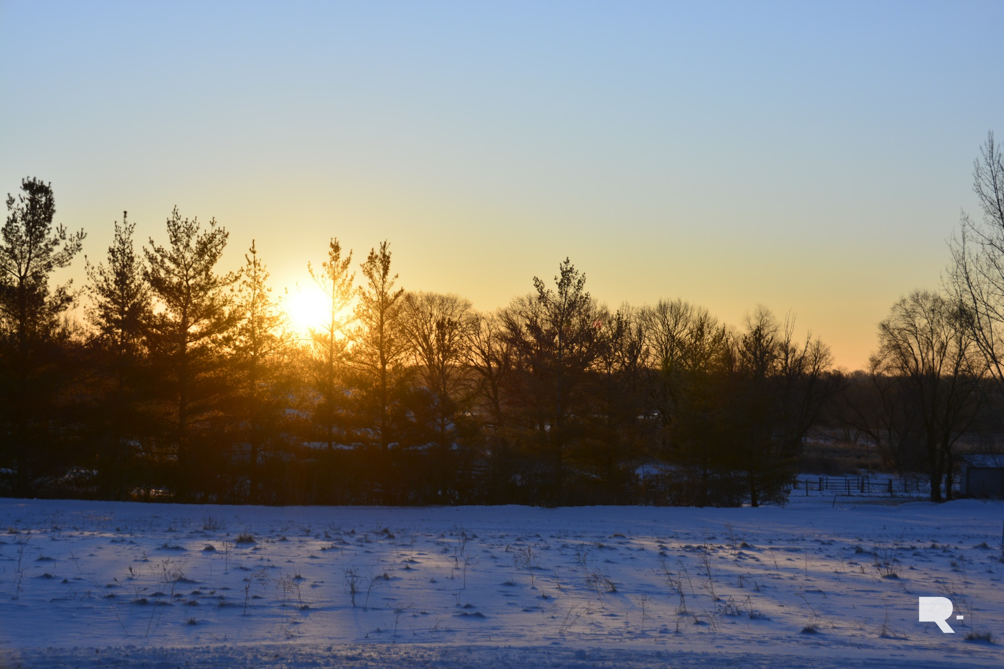 Winter landscape with snow-covered field and low morning sun